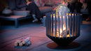 Cos de foc RedFire Irving Large aprins intr-o gradina, langa mobilier de exterior
