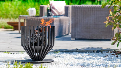 Cos de foc RedFire Irving Medium aprins pe o terasa stropita de zapada, langa mobilier de exterior