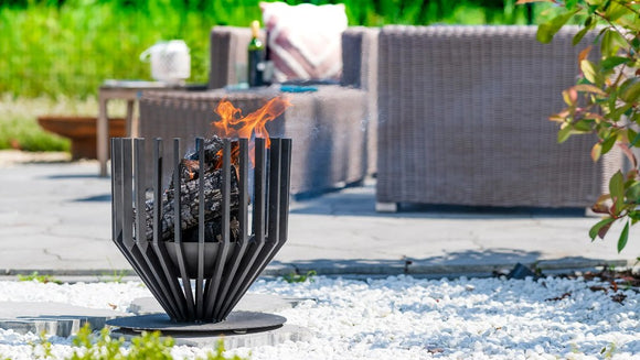 Cos de foc RedFire Irving Medium aprins pe o terasa stropita de zapada, langa mobilier de exterior