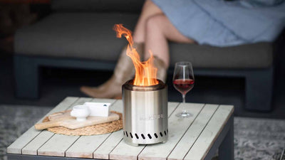 Vatra RedFire Volcano Medium aprinsa pe o masa de terasa, cu pahar de vin alaturi