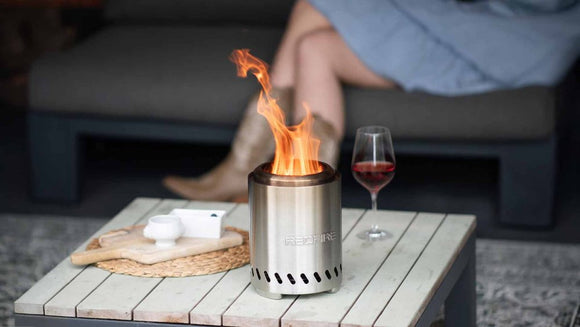 Vatra RedFire Volcano Medium aprinsa pe o masa de terasa, cu pahar de vin alaturi