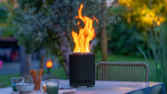 Vatra RedFire Volcano Medium aprinsa seara, pe o masa in gradina